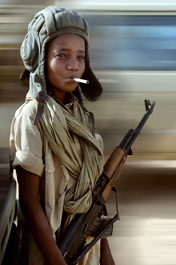 A child soldier poses with a libyan helm